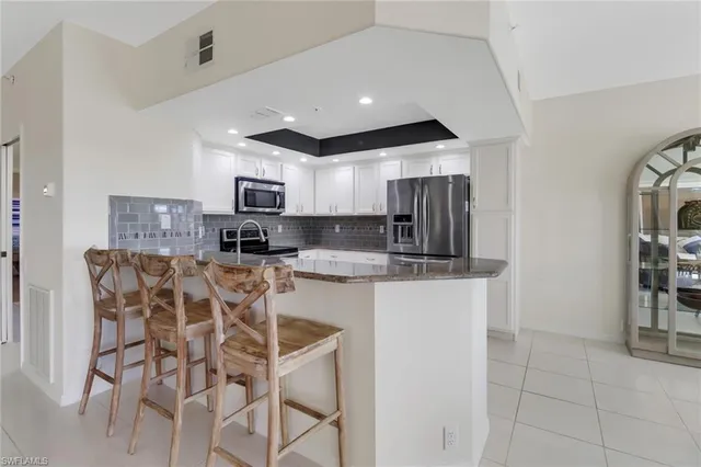 a kitchen with stainless steel appliances granite countertop a stove top oven a sink a dining table and chairs