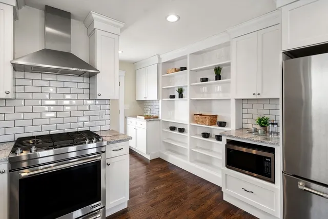a kitchen with cabinets stainless steel appliances and wooden floor