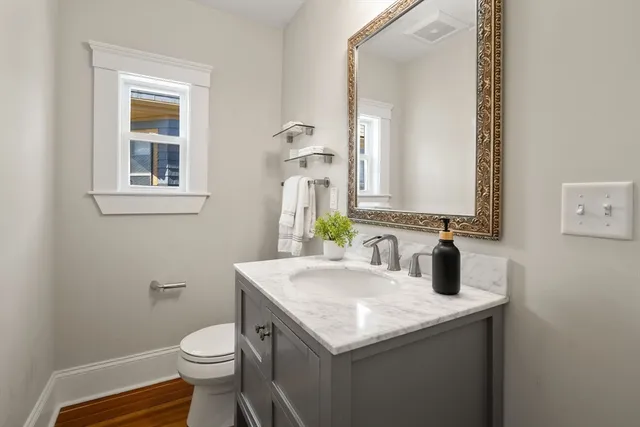 a bathroom with a granite countertop toilet sink and mirror
