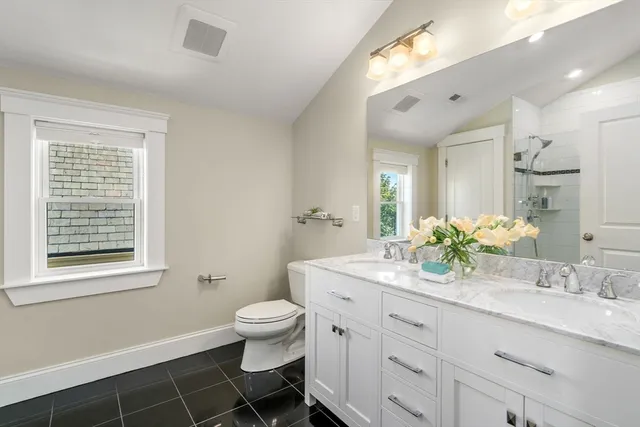 a spacious bathroom with a double vanity sink toilet and a mirror