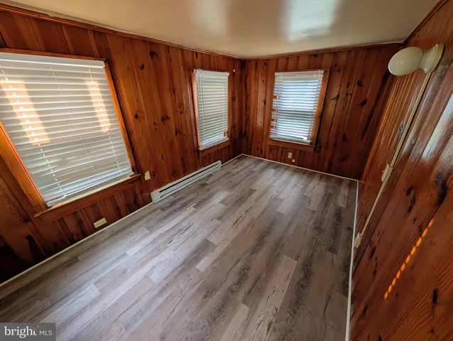 a view of an empty room with wooden floor and window