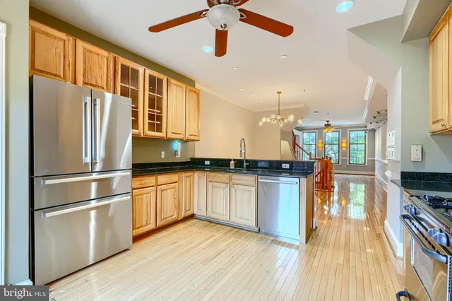 a kitchen with stainless steel appliances granite countertop a refrigerator a stove and a wooden floors