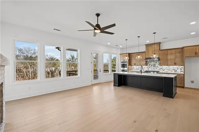 a living room with stainless steel appliances kitchen island granite countertop a stove a sink a refrigerator cabinets and a window