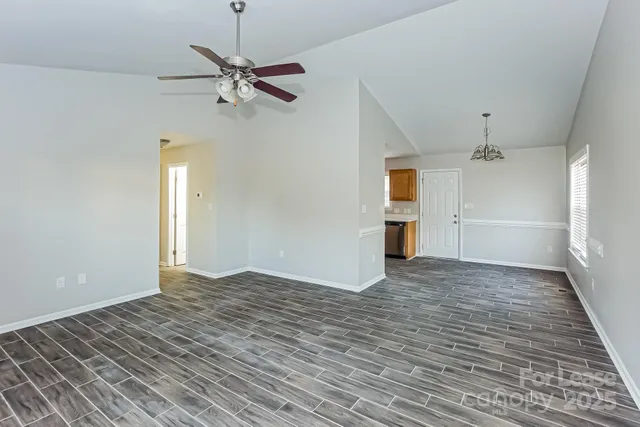 a view of empty room with wooden floor and ceiling fan