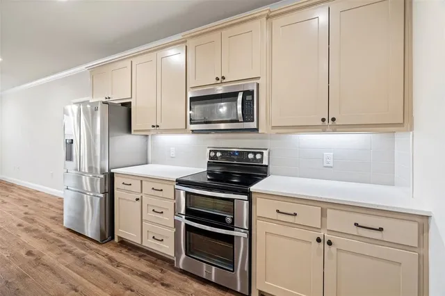 a kitchen with cabinets stainless steel appliances and wooden floor