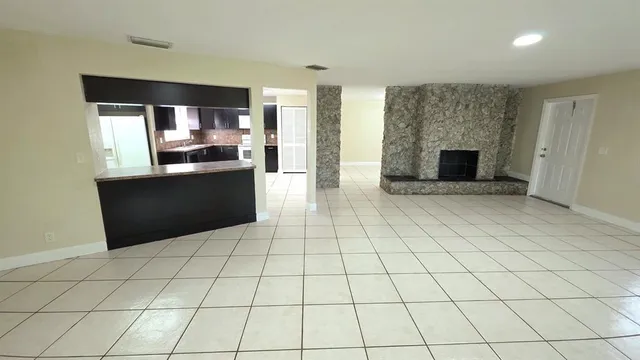 a view of empty room with kitchen and fireplace