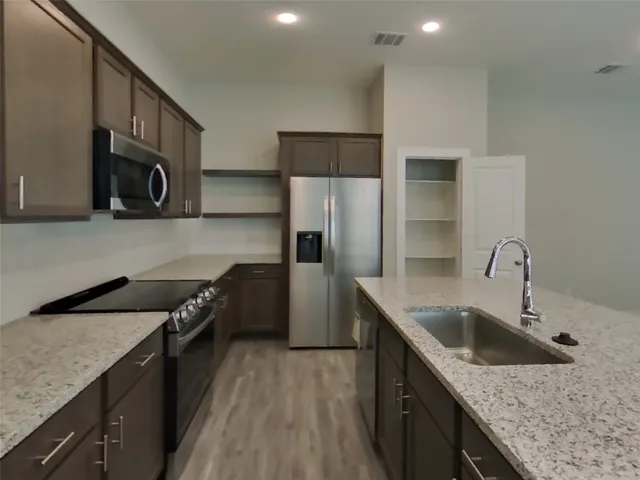 a kitchen with stainless steel appliances granite countertop a sink stove and refrigerator