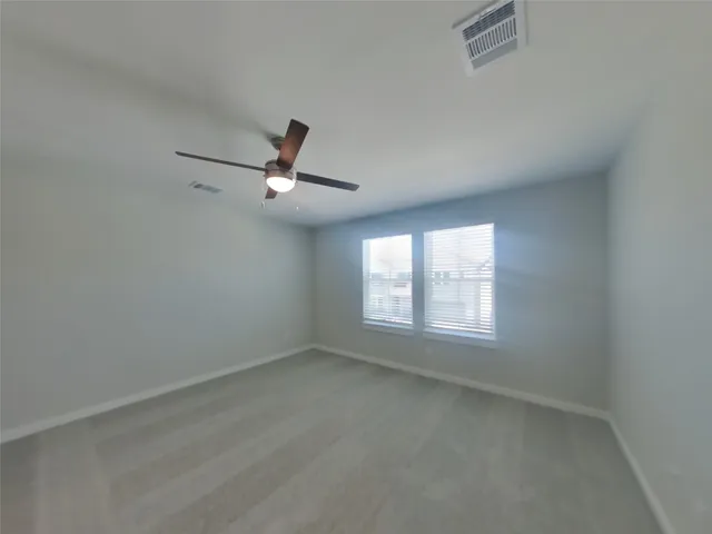 an empty room with a window and a ceiling fan