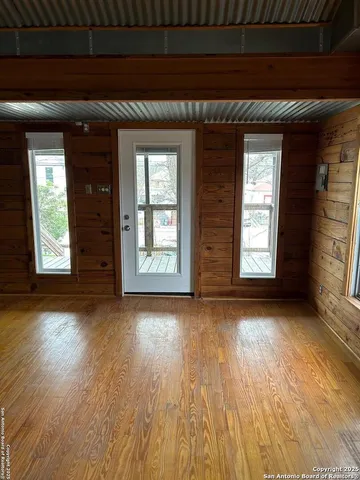 an empty room with wooden floor and windows