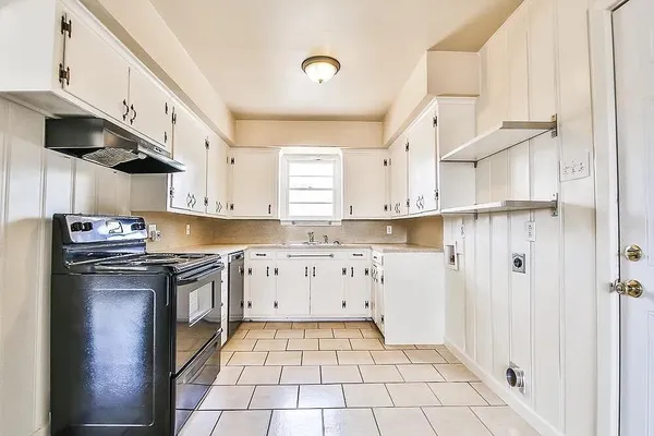 a kitchen with granite countertop a stove a sink and a refrigerator