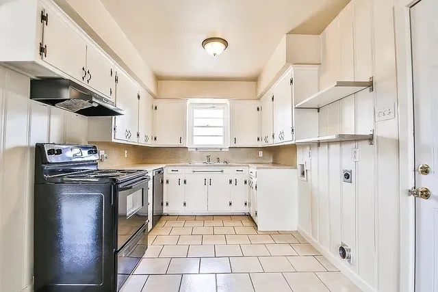 a kitchen with granite countertop a stove a sink and a refrigerator