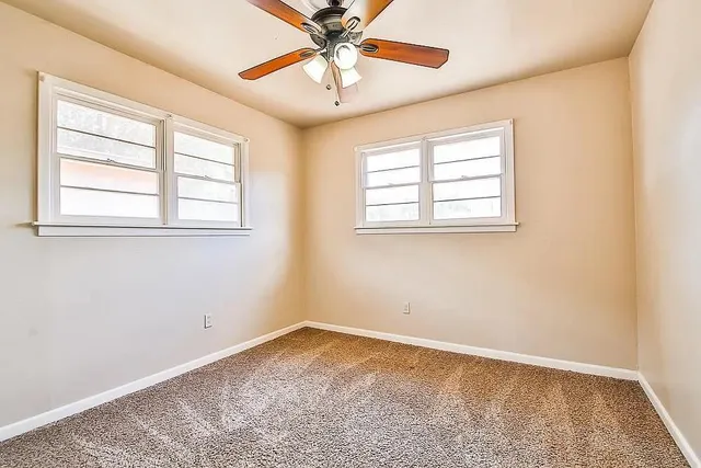 an empty room with a window and a fan
