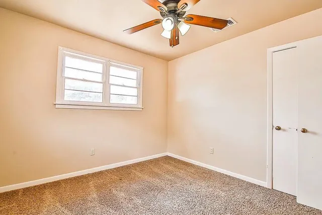 an empty room with a window and a fan