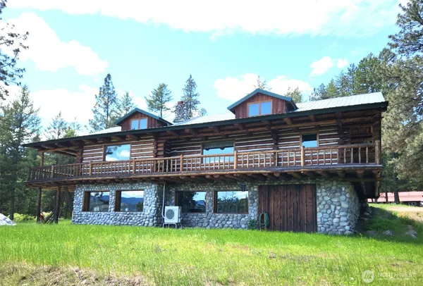 a view of a brick house with a yard potted plants and a large tree