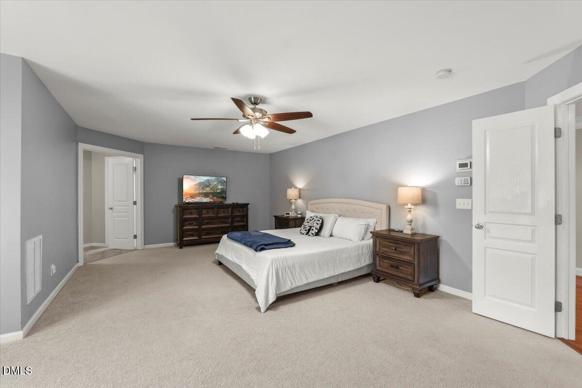 7828 Percussion Drive Apex, NC 27539 - Photo 44 of 88 a spacious bedroom with a bed and a chandelier
