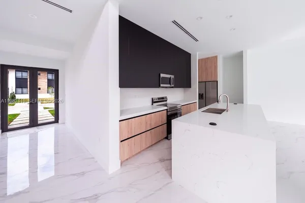 a living room with stainless steel appliances furniture a flat screen tv and a kitchen view