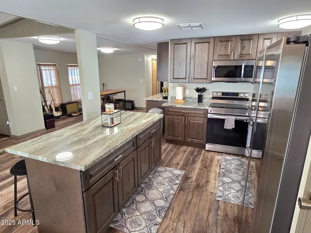 a kitchen with stainless steel appliances granite countertop a sink stove microwave and refrigerator