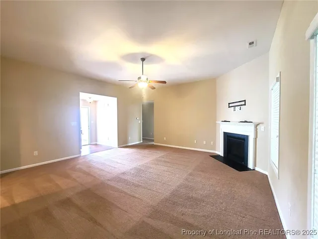 an empty room with windows and fireplace