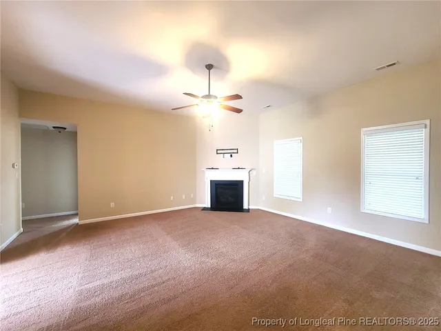 an empty room with windows and fireplace