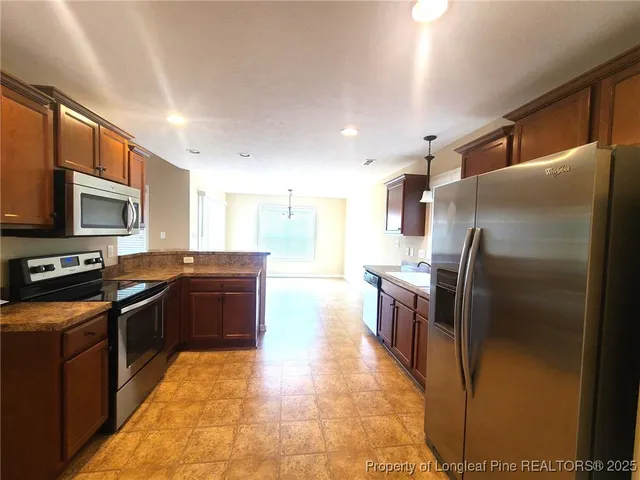 a large kitchen with a large counter top stainless steel appliances and cabinets