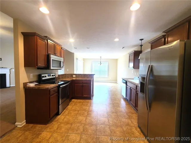 a kitchen with granite countertop a refrigerator and a stove top oven