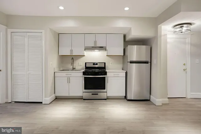 a kitchen with stainless steel appliances a refrigerator and white cabinets