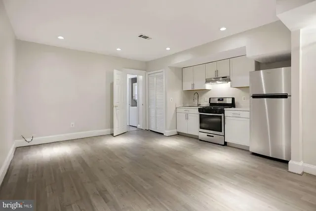 a view of kitchen with stainless steel appliances wooden floor and window