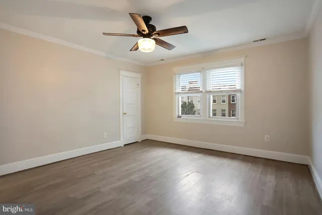 an empty room with wooden floor fan and windows