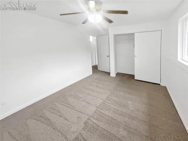 an empty room with closet and a ceiling fan