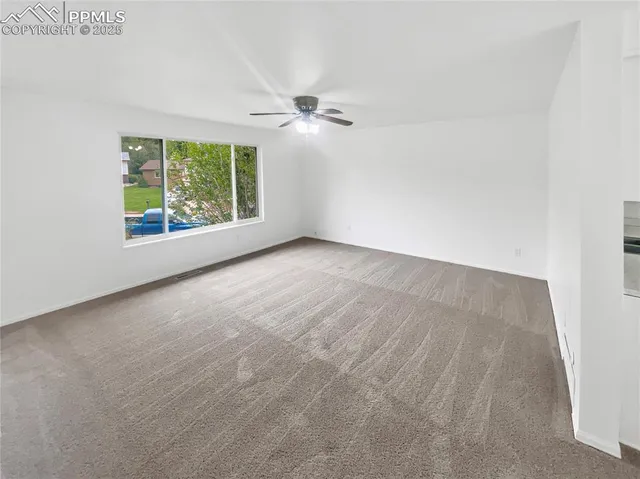 an empty room with windows and ceiling fan