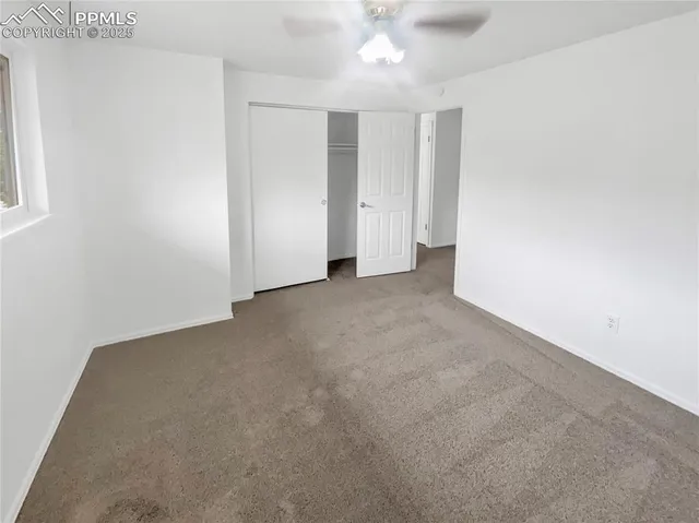 an empty room with a ceiling fan and a window