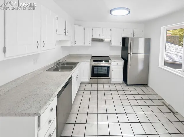 a kitchen with a stove a refrigerator and white cabinets