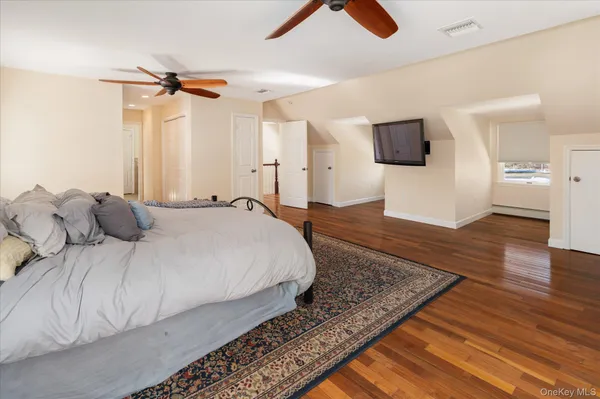 a large bedroom with a bed and flat tv screen on the dresser