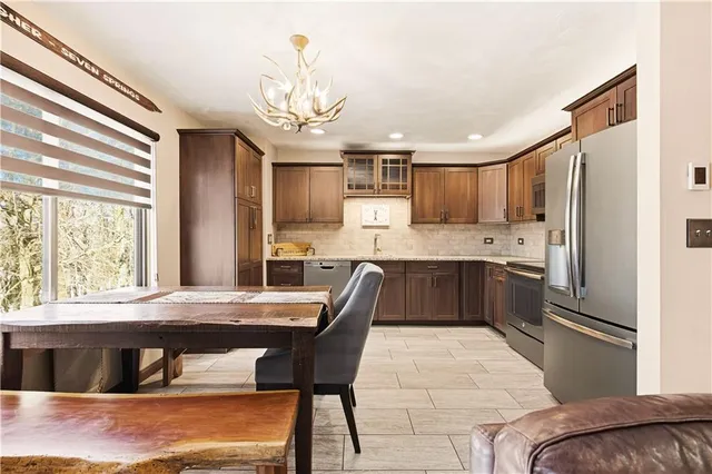 a kitchen with stainless steel appliances kitchen island granite countertop a sink dishwasher a stove a refrigerator with a dining table and chairs