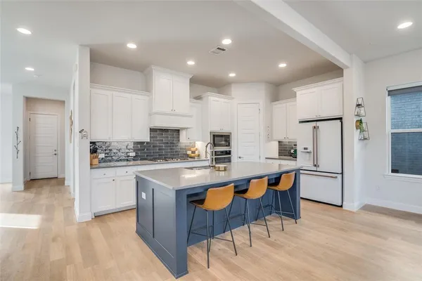 a kitchen with stainless steel appliances granite countertop a table chairs sink refrigerator and cabinets