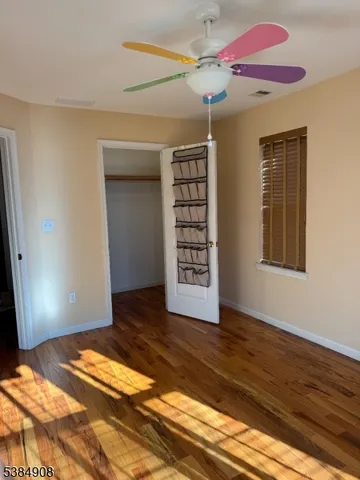 a view of an empty room with window and wooden floor