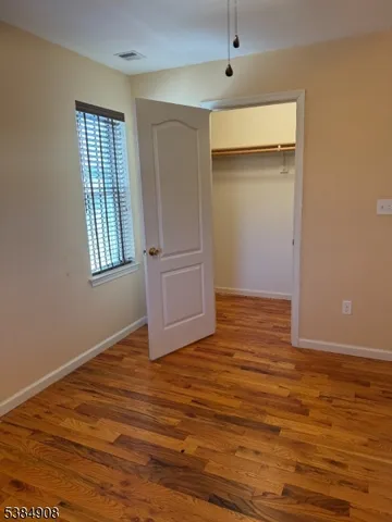 an empty room with wooden floor and cabinet
