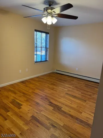 a view of an empty room with window and chandelier fan
