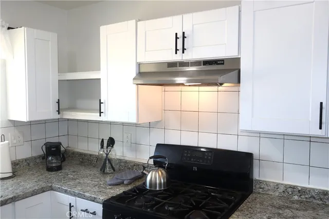 a kitchen with granite countertop a sink stove and cabinets