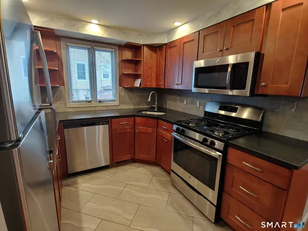 a kitchen with stainless steel appliances granite countertop a stove top oven a sink dishwasher and a microwave oven on the blue kitchen countertops