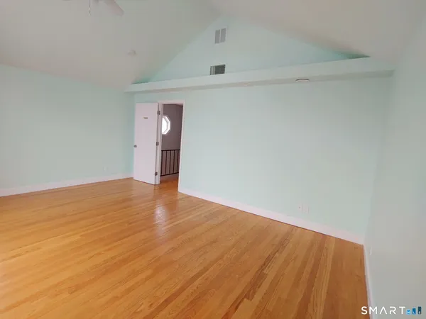 a view of an empty room with wooden floor and closet