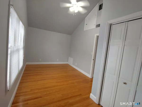a view of empty room with wooden floor and fan