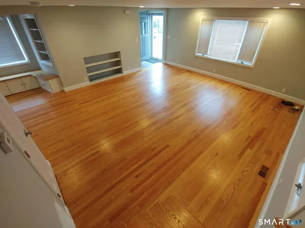 a view of an empty room with wooden floor and a window
