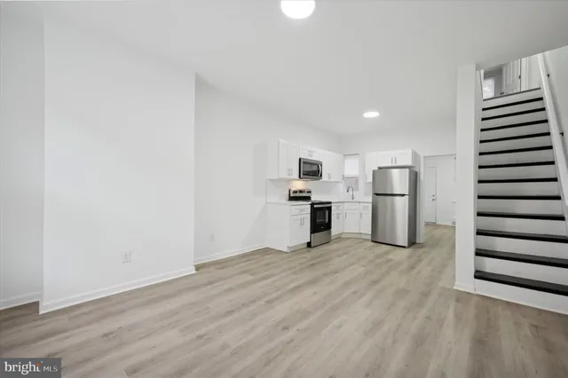 a view of kitchen with wooden floor electronic appliances and stairs