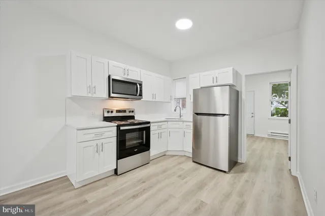 a kitchen with a refrigerator stove and white cabinets