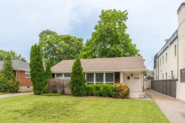 a front view of a house with a yard and potted plants