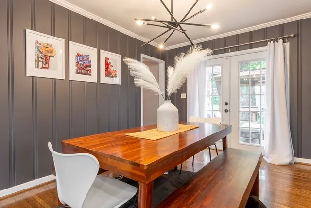 a dining room with wooden floor a chandelier a wooden table and chairs