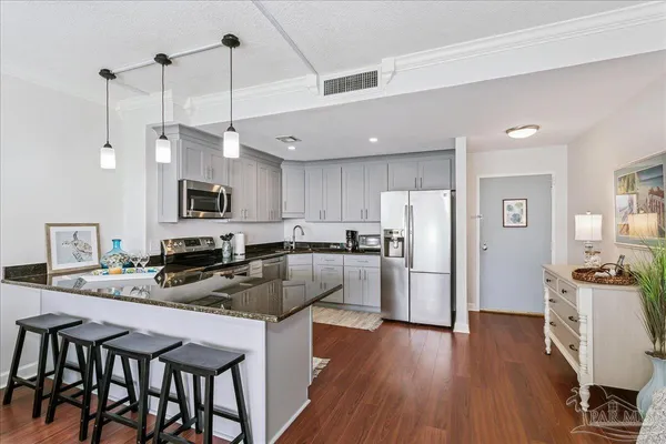 a kitchen with refrigerator a stove and wooden floor