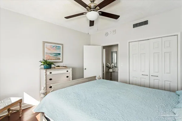 a bedroom with a large bed and a chandelier fan