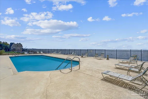 a view of a swimming pool with chair and dinning table under an umbrella